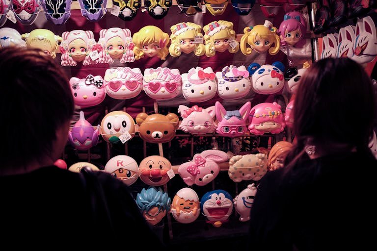 Colorful anime masks for sale at a bustling Tokyo market stall, Japan.